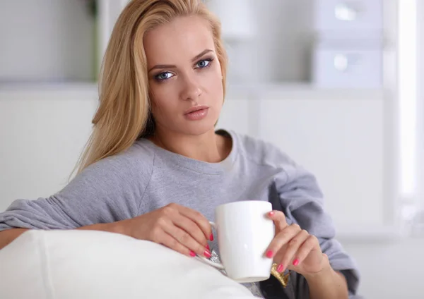 Mujer sentada en el sofá con la taza en las manos —  Fotos de Stock