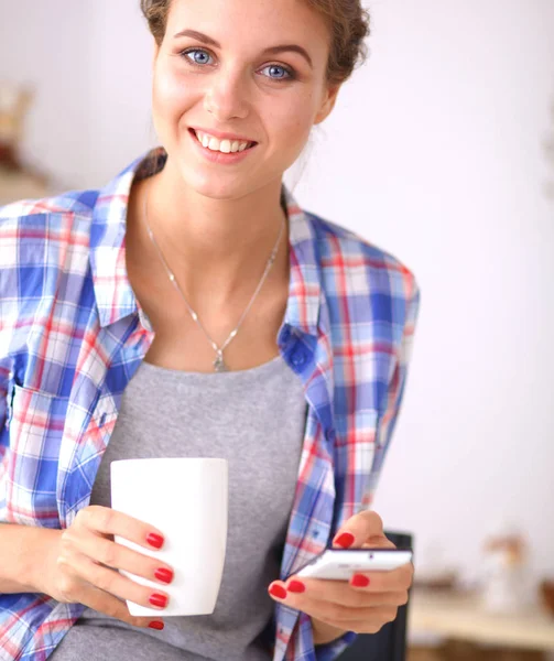 Glimlachende vrouw met haar mobiele telefoon in de keuken — Stockfoto