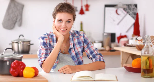 Mujer joven leyendo libro de cocina en la cocina, buscando receta —  Fotos de Stock