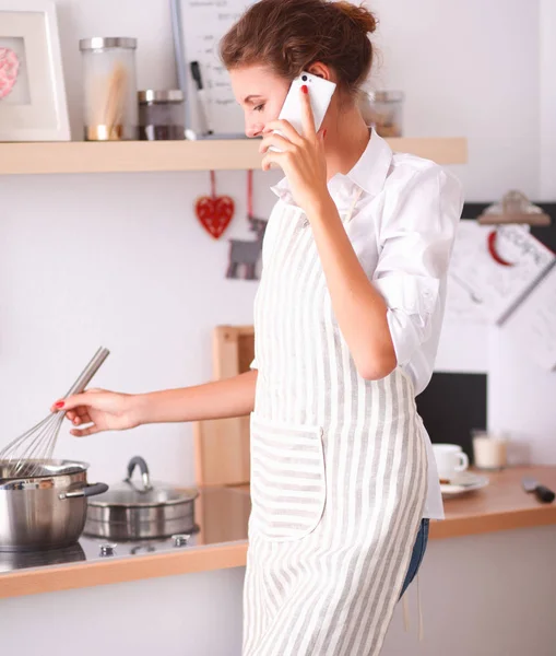 Porträtt en leende kvinna med telefon i köket hemma — Stockfoto