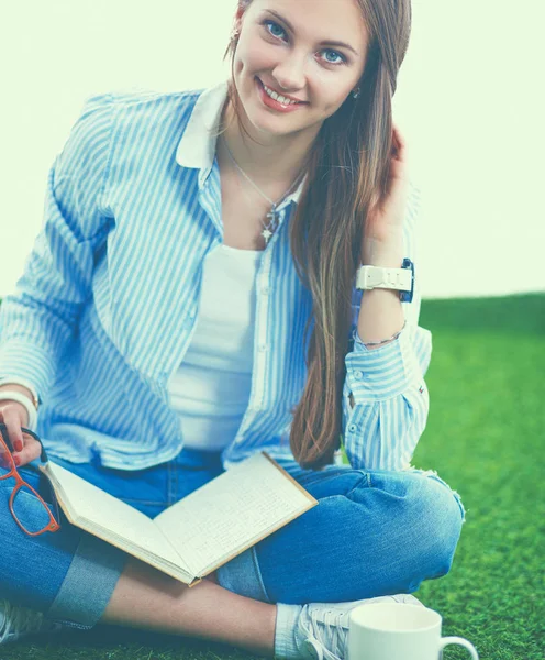 Young woman sitting with book on grass — Stock Photo, Image