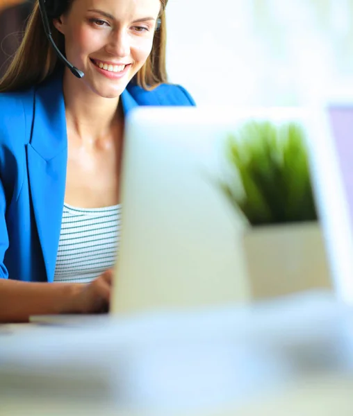 Porträtt av vacker affärskvinna som arbetar vid sitt skrivbord med headset och laptop. — Stockfoto