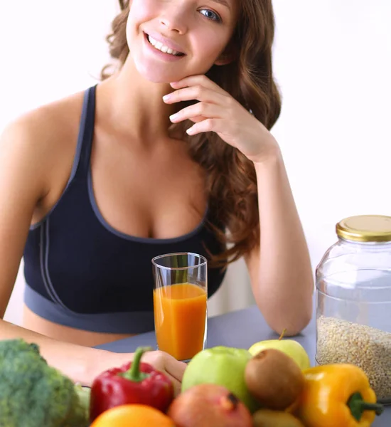 Chica sentada en la cocina en el escritorio con frutas y vasos con jugo — Foto de Stock