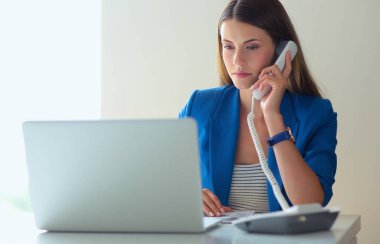 Telefon bir dizüstü bilgisayar önünde genç kadın portre
