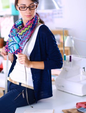 Güzel moda tasarımcısı stüdyoda duruyor.