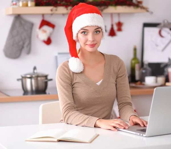 Glimlachende jonge vrouw in de keuken, geïsoleerd op kerst achtergrond — Stockfoto