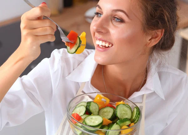 Ung kvinna äter färsk sallad i modernt kök — Stockfoto