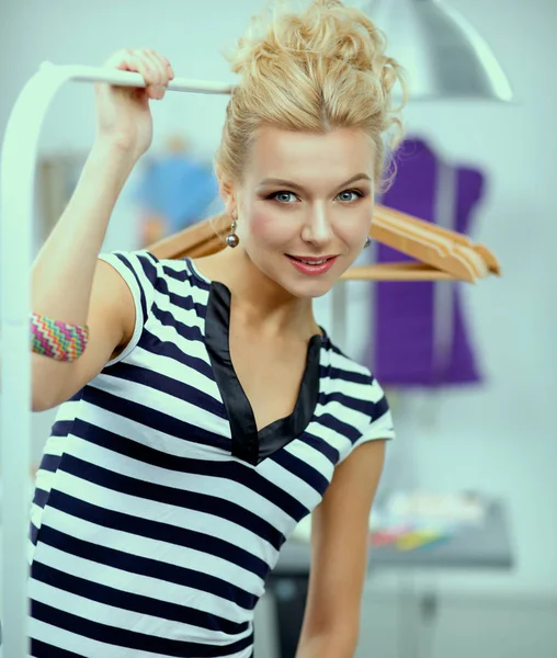 Beautiful young stylist woman near rack with hangers — Stock Photo, Image