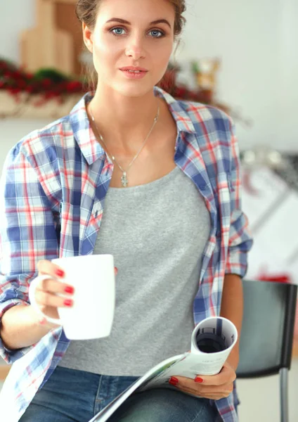 Mujer sonriente sosteniendo su teléfono celular en la cocina — Foto de Stock