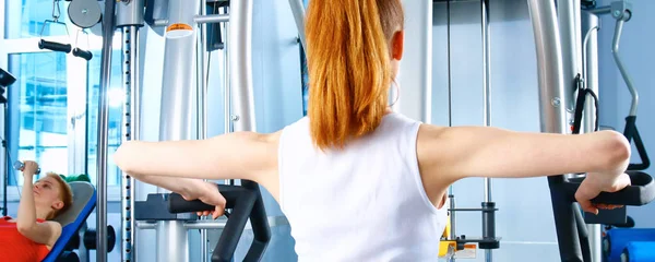 Bella ragazza in palestra che si esercita sugli allenatori — Foto Stock