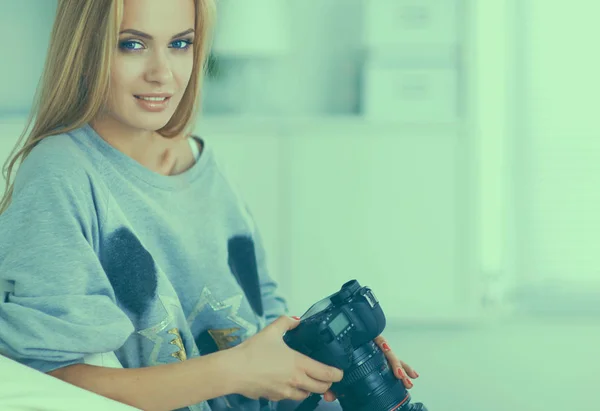 Woman sitting on a sofa in her house with camera — Stock Photo, Image