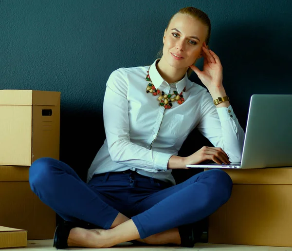 Frau sitzt auf dem Boden neben einer Schachtel mit Laptop — Stockfoto
