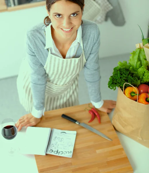 Женщина делает здоровую пищу стоя улыбаясь на кухне — стоковое фото