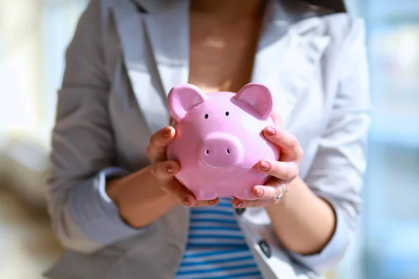 Young beautiful woman standing with piggy bank money box, on building — Stock Photo, Image