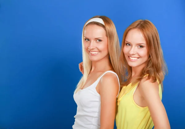 Primo piano ritratto di due donne sorridenti isolate su sfondo blu — Foto Stock