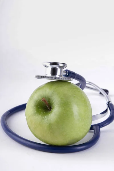 Stethoscope és zöld alma elszigetelt fehér alapon — Stock Fotó