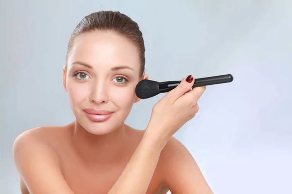 Porträt einer attraktiven jungen erwachsenen Frau mit Make-up-Pinsel — Stockfoto