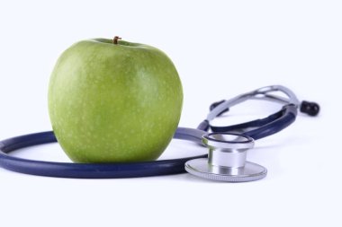 Stetoskop ve yeşil elma beyaz arkaplanda izole edilmiş.