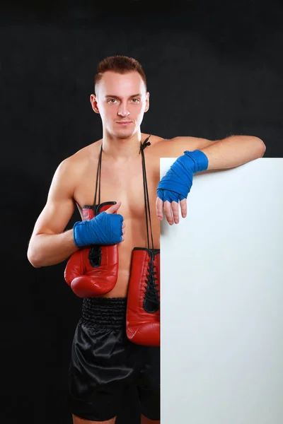 Młody przystojny bokser człowiek stojący w pobliżu zarządu, na białym tle na czarnym tle — Zdjęcie stockowe