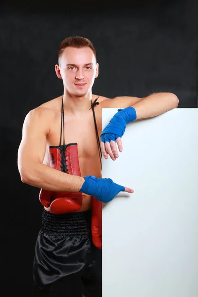 Jovem bonito boxeador homem de pé perto de bordo, isolado no fundo preto — Fotografia de Stock