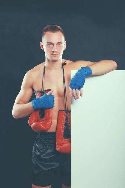 Junger gutaussehender Boxer, der in der Nähe von Bord steht, isoliert auf schwarzem Hintergrund — Stockfoto