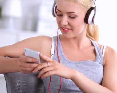 Evdeki genç ve güzel kadın kanepede oturup müzik dinliyor.