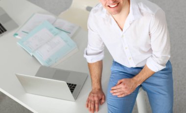 Genç işadamı ofiste çalışıyor, masada oturuyor.