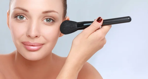 Portret van aantrekkelijke jonge volwassen vrouw met make-up borstel — Stockfoto