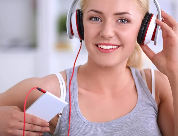 Jeune belle femme à la maison assise sur un canapé et écoutant de la musique — Photo