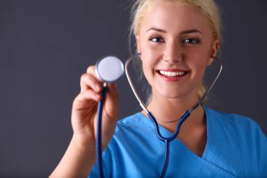 Steteskopla dinleyen kadın doktor, gri arka planda izole edilmiş.