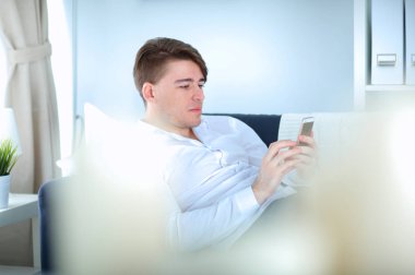 Genç işadamı ofiste çalışıyor, masada oturuyor.