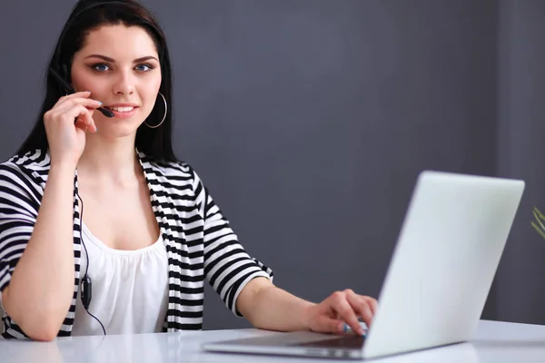 Mulher de negócios bonita trabalhando em sua mesa com fone de ouvido e laptop — Fotografia de Stock