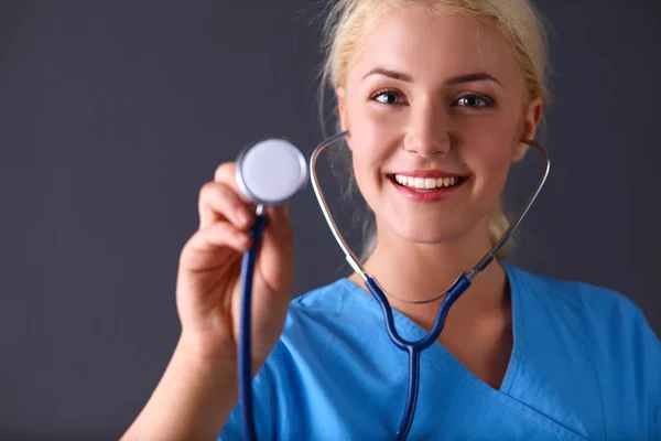 Vrouwelijke arts met een stethoscoop luisteren, geïsoleerd op grijze achtergrond — Stockfoto