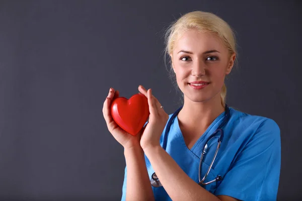 Young doctor woman with stethoscope holding heart — Stock Photo, Image