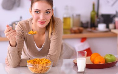 Gülümseyen çekici kadın mutfağın içinde kahvaltı yapıyor.