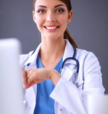 Gri arka planda oturan kadın doktor