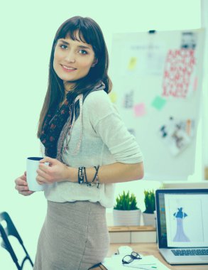 Genç çekici moda Ofis Masası tarafından ayakta, Kupası tutan Tasarımcısı