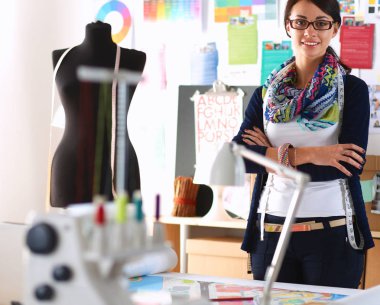 Güzel moda tasarımcısı stüdyoda duruyor.