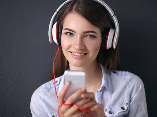 Menina sorridente com fones de ouvido sentado no chão perto da parede — Fotografia de Stock