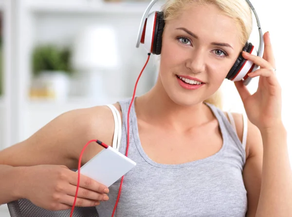 Joven hermosa mujer en casa sentada en el sofá y escuchando música —  Fotos de Stock