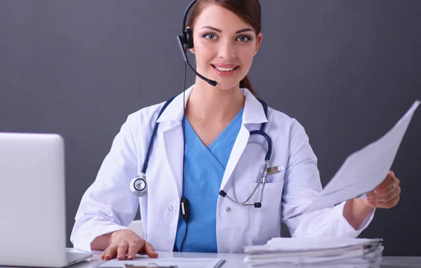 Doctor wearing headset sitting behind a desk with laptop — Stock Photo, Image