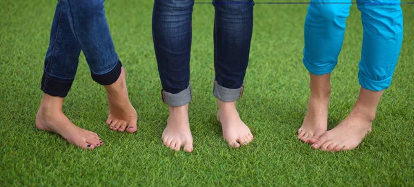 Tres mujeres con los pies desnudos de pie en la hierba — Foto de Stock