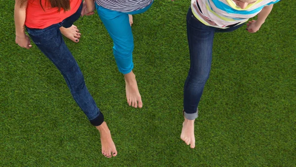 Три женщины с голыми ногами стоят в траве — стоковое фото