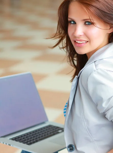 Unga leende kvinna sitter med bärbar dator — Stockfoto