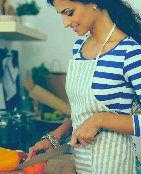 Jonge vrouw snijden groenten in de keuken — Stockfoto