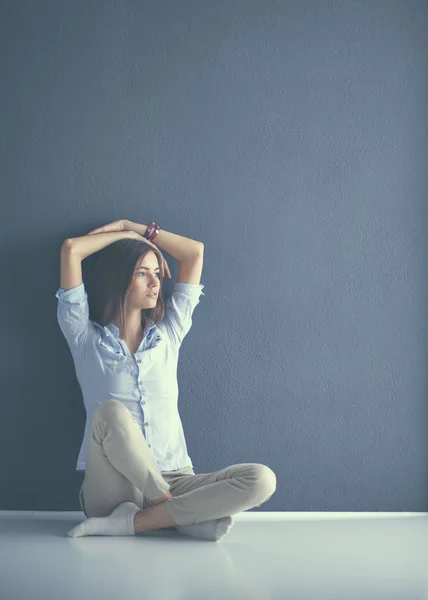 Young woman sitting on the floor near dark wall — Stock Photo, Image