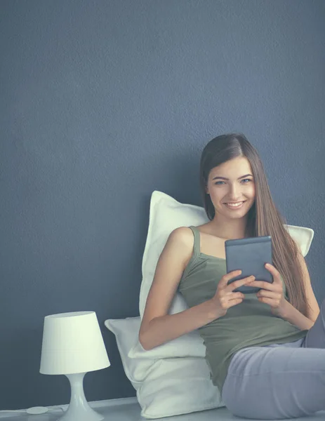 Mujer morena bonita sentada en el suelo con una almohada y mesa de avión — Foto de Stock