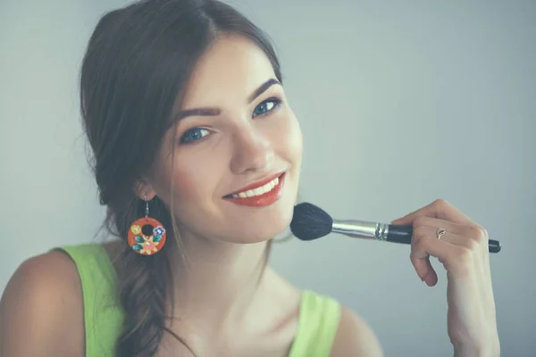 Jonge mooie vrouw maken make-up in de buurt van spiegel, zitten aan de balie — Stockfoto