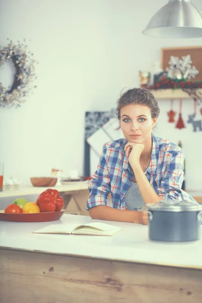 Mujer joven leyendo libro de cocina en la cocina, buscando receta —  Fotos de Stock