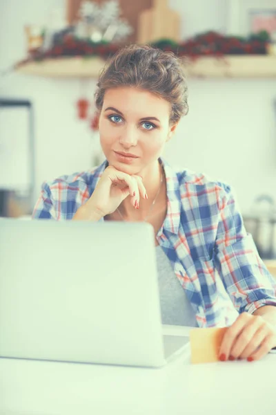 Mujer sonriente compras en línea utilizando la computadora y la tarjeta de crédito en la cocina —  Fotos de Stock